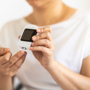 Close up of woman hands using Glucose meter on finger to check b